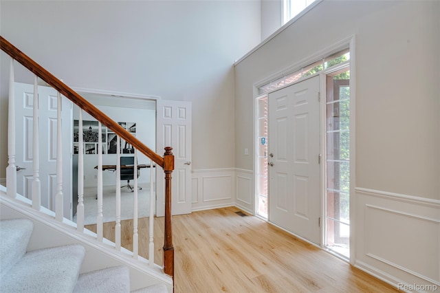 50042 Black Horse Ln, Canton, MI 48188 - entrance foyer featuring stairway, a decorative wall, wood finished floors, a wainscoted wall, and a high ceiling