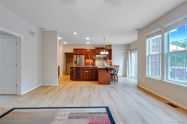 50042 Black Horse Ln, Canton, MI 48188 - kitchen with stainless steel fridge with ice dispenser, light wood-style floors, a breakfast bar, an island with sink, and hanging light fixtures