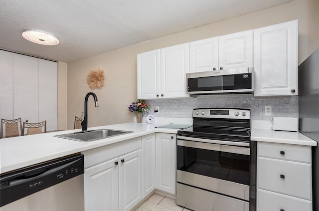 100 4th Ave, Tawas City, MI 48763 - kitchen with stainless steel appliances, backsplash, light countertops, white cabinets, and a textured ceiling