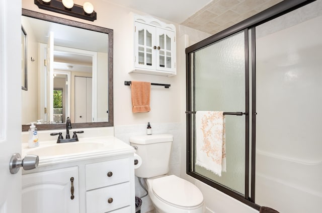 100 4th Ave, Tawas City, MI 48763 - bathroom featuring vanity, wainscoting, tile walls, and bath / shower combo with glass door