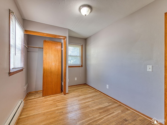 855 Mildred Ave, Temperance, MI 48182 - unfurnished bedroom featuring a baseboard heating unit, light wood-style floors, and a closet