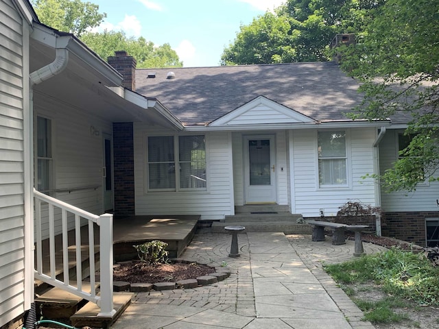 4442 Congdon Dr, Williamston, MI 48895 - property entrance featuring a chimney, roof with shingles, and a patio area