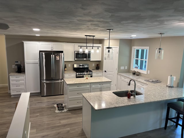 4442 Congdon Dr, Williamston, MI 48895 - kitchen featuring appliances with stainless steel finishes, white cabinets, light stone countertops, a breakfast bar area, and recessed lighting