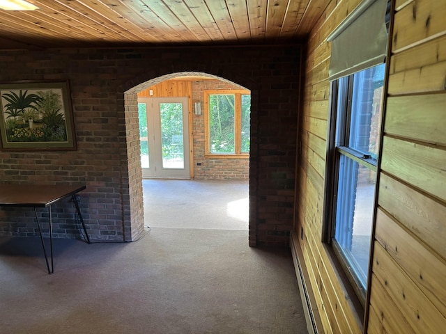 4442 Congdon Dr, Williamston, MI 48895 - hall featuring carpet flooring, wood ceiling, brick wall, wooden walls, and a baseboard radiator