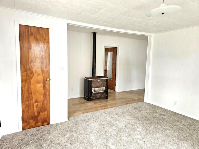 109 W Woodrow St, Fremont, MI 49412 - carpeted empty room with a wood stove, crown molding, and wooden walls