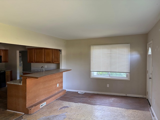 4299 N Belsay Rd, Flint, MI 48506 - kitchen with dark wood-type flooring, a peninsula, brown cabinets, stove, and a kitchen breakfast bar