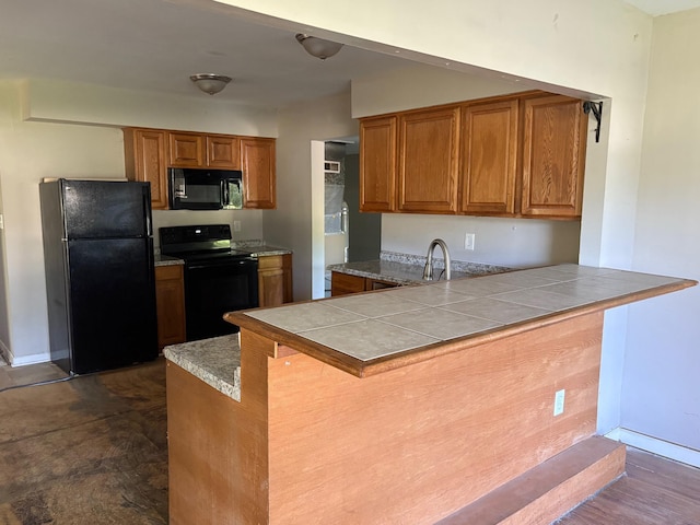 4299 N Belsay Rd, Flint, MI 48506 - kitchen featuring black appliances, brown cabinets, a kitchen bar, and a peninsula
