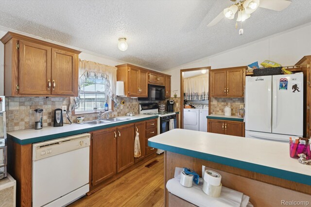 4591 Swaffer Rd, Millington, MI 48746 - kitchen with white appliances, washing machine and clothes dryer, a textured ceiling, vaulted ceiling, and light countertops