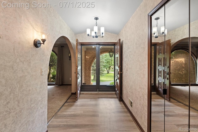 945 E Gunn Rd, Rochester, MI 48306 - entrance foyer featuring arched walkways, a chandelier, vaulted ceiling, wood finished floors, and a textured wall