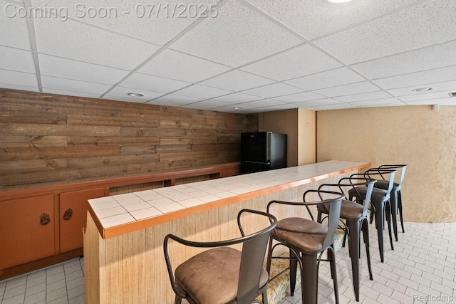 945 E Gunn Rd, Rochester, MI 48306 - indoor bar featuring freestanding refrigerator, light tile patterned floors, a drop ceiling, and wood walls