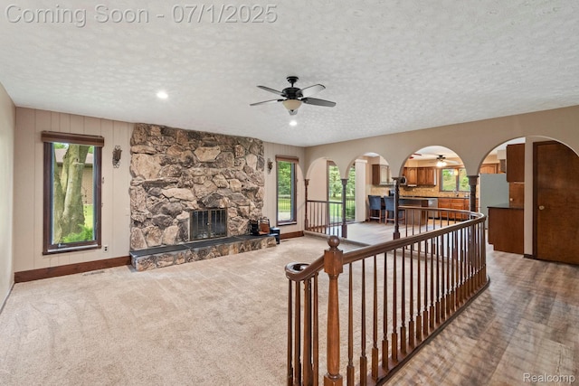945 E Gunn Rd, Rochester, MI 48306 - carpeted living room with a ceiling fan, a textured ceiling, a stone fireplace, arched walkways, and recessed lighting