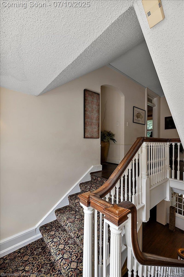 777 Kensington Ln, Bloomfield Hills, MI 48304 - stairs with arched walkways, vaulted ceiling, and a textured ceiling
