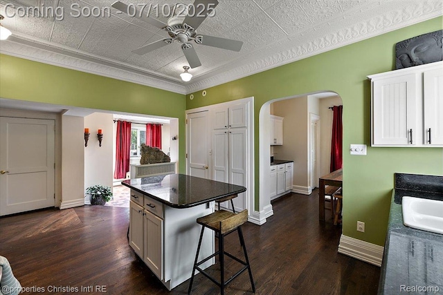 777 Kensington Ln, Bloomfield Hills, MI 48304 - kitchen featuring a ceiling fan, dark countertops, dark wood-style flooring, arched walkways, and a kitchen bar