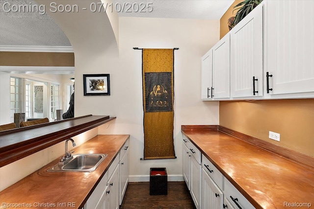 777 Kensington Ln, Bloomfield Hills, MI 48304 - kitchen featuring butcher block countertops, a textured ceiling, white cabinetry, ornamental molding, and dark wood-type flooring