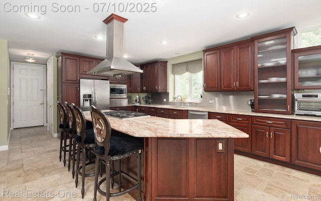 6120 Evanswood Rd, Troy, MI 48085 - kitchen featuring island exhaust hood, appliances with stainless steel finishes, light stone finish floors, a kitchen island, and a breakfast bar area