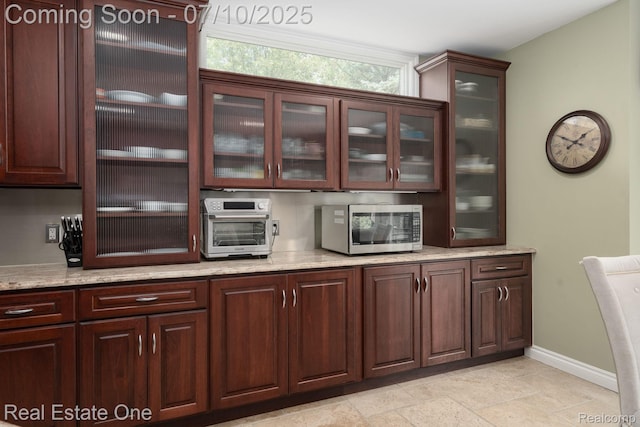 6120 Evanswood Rd, Troy, MI 48085 - kitchen with stainless steel microwave, light stone counters, glass insert cabinets, and dark brown cabinets