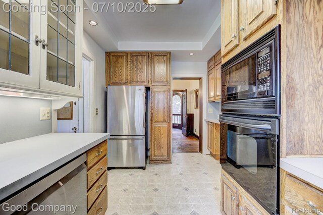 66 Oakdale Blvd, Pleasant Ridge, MI 48069 - kitchen featuring appliances with stainless steel finishes, light countertops, a raised ceiling, brown cabinetry, and glass insert cabinets