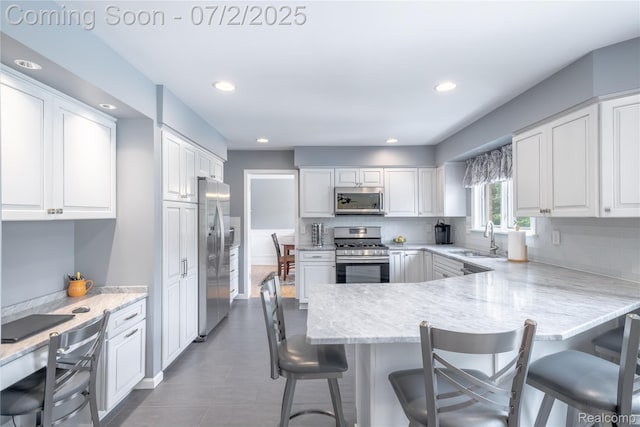 11216 Old Bridge Rd, Grand Blanc, MI 48439 - kitchen with stainless steel appliances, white cabinetry, a peninsula, decorative backsplash, and recessed lighting