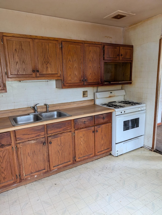 2606 Laredo St, Kalamazoo, MI 49004 - kitchen with white range with gas stovetop, light countertops, brown cabinetry, and light floors