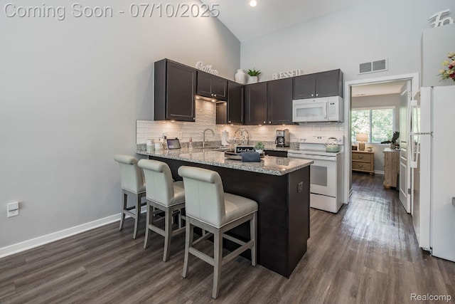 2489 Hatchery Crossing Dr, Waterford, MI 48329 - kitchen with white appliances, high vaulted ceiling, backsplash, dark wood-style flooring, and a peninsula