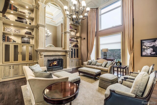18198 Shelley Pond, Northville, MI 48168 - living area with a chandelier, built in shelves, a towering ceiling, a fireplace, and dark wood finished floors
