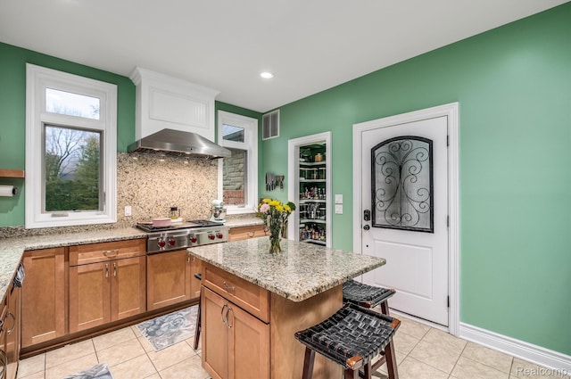 18198 Shelley Pond, Northville, MI 48168 - kitchen with light tile patterned flooring, stainless steel gas stovetop, wall chimney range hood, tasteful backsplash, and light stone counters