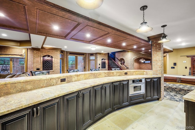 18198 Shelley Pond, Northville, MI 48168 - kitchen featuring stainless steel oven, hanging light fixtures, light stone countertops, dark cabinetry, and ornate columns