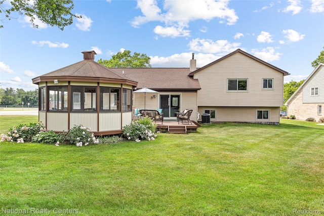 1306 Bishops Ter, Wixom, MI 48393 - back of property featuring a chimney, a deck, a yard, a sunroom, and roof with shingles