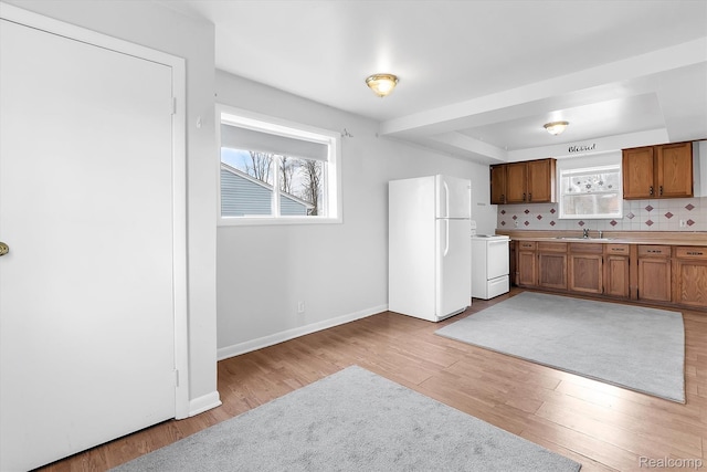 322 Michelson Rd, Rochester Hills, MI 48307 - kitchen featuring white appliances, light wood finished floors, brown cabinetry, a tray ceiling, and light countertops