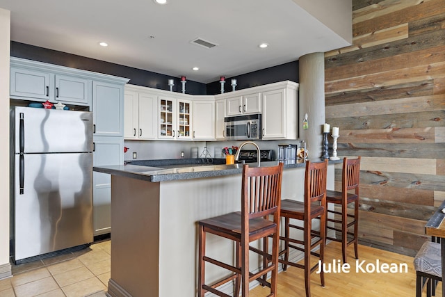930 Washington Ave Unit 5C, Muskegon, MI 49441 - kitchen featuring appliances with stainless steel finishes, dark countertops, glass insert cabinets, a peninsula, and white cabinets