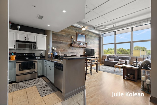 930 Washington Ave Unit 5C, Muskegon, MI 49441 - kitchen featuring appliances with stainless steel finishes, dark countertops, wood walls, open floor plan, and white cabinetry
