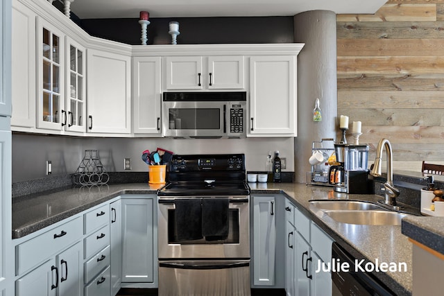930 Washington Ave Unit 5C, Muskegon, MI 49441 - kitchen featuring appliances with stainless steel finishes, white cabinets, wooden walls, glass insert cabinets, and dark stone countertops