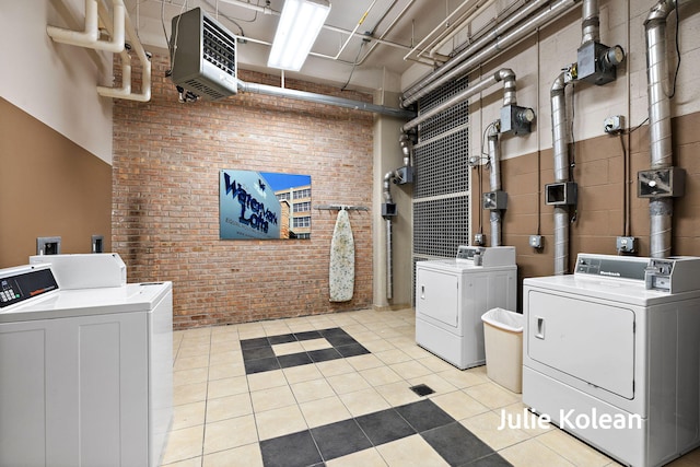 930 Washington Ave Unit 5C, Muskegon, MI 49441 - community laundry room with washing machine and dryer, brick wall, a heating unit, and light tile patterned flooring