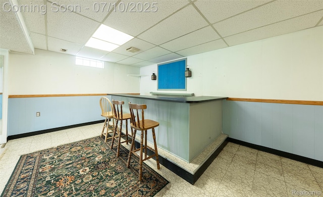 2150 Dunwoodie St, Ortonville, MI 48462 - indoor dry bar featuring tile patterned floors, a paneled ceiling, wooden walls, and wainscoting