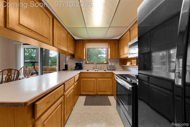 2150 Dunwoodie St, Ortonville, MI 48462 - kitchen with stainless steel appliances, light countertops, a peninsula, brown cabinets, and a drop ceiling