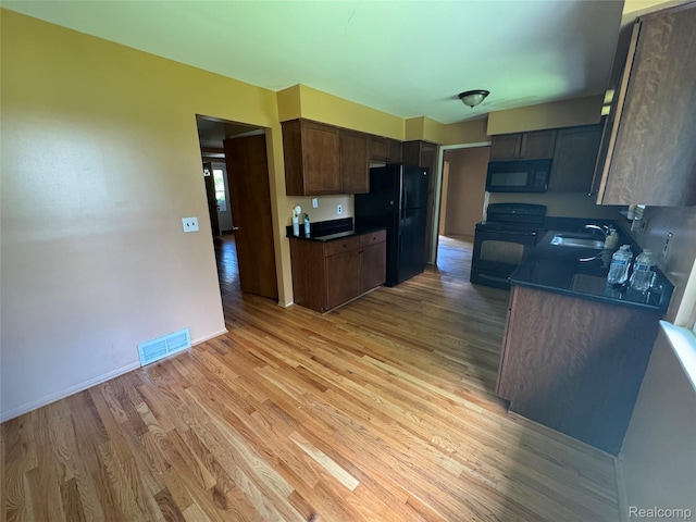 28330 Lahser Rd, Southfield, MI 48034 - kitchen featuring black appliances, dark countertops, and light wood finished floors
