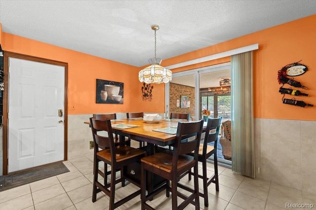 20213 Whitby Dr, Livonia, MI 48152 - dining space with tile walls, light tile patterned floors, a wainscoted wall, a chandelier, and a textured ceiling