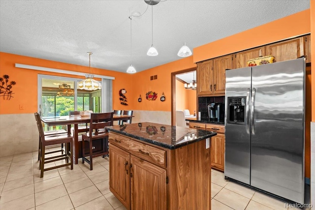 20213 Whitby Dr, Livonia, MI 48152 - kitchen featuring stainless steel fridge with ice dispenser, brown cabinets, light tile patterned floors, a center island, and a textured ceiling