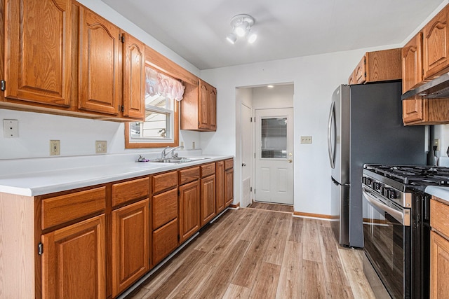 981 Vinewood Dr, Saint Joseph, MI 49085 - kitchen featuring stainless steel range with gas stovetop, light wood-style floors, brown cabinetry, and light countertops