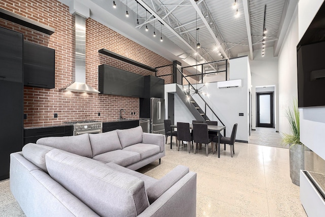 220 King St Unit 6, Lowell, MI 49331 - living area with a towering ceiling, track lighting, a wall mounted AC, dark speckled floor, and brick wall
