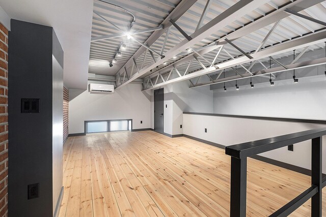220 King St Unit 6, Lowell, MI 49331 - empty room with an AC wall unit, track lighting, hardwood / wood-style flooring, and brick wall