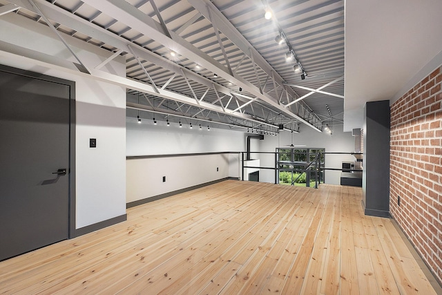 220 King St Unit 6, Lowell, MI 49331 - spare room featuring brick wall, rail lighting, and hardwood / wood-style floors