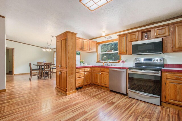 2919 N US Highway 31, Niles, MI 49120 - kitchen with appliances with stainless steel finishes, tile countertops, light wood finished floors, brown cabinetry, and a textured ceiling