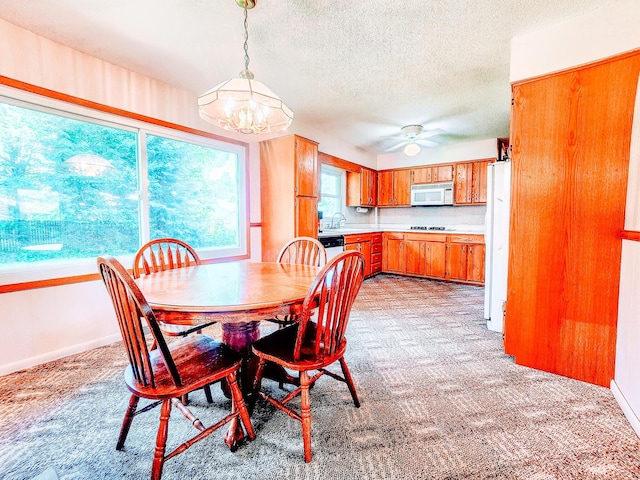 671 Lonesome Pine Trl, Saint Joseph, MI 49085 - dining area featuring a chandelier, light colored carpet, a textured ceiling, and a ceiling fan