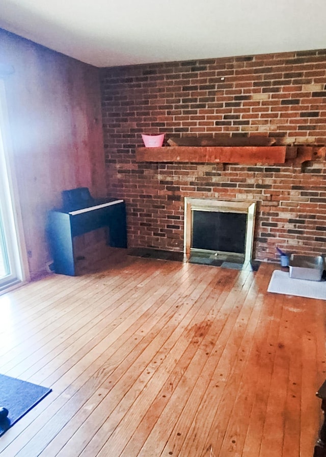 671 Lonesome Pine Trl, Saint Joseph, MI 49085 - unfurnished living room with hardwood / wood-style flooring and a brick fireplace