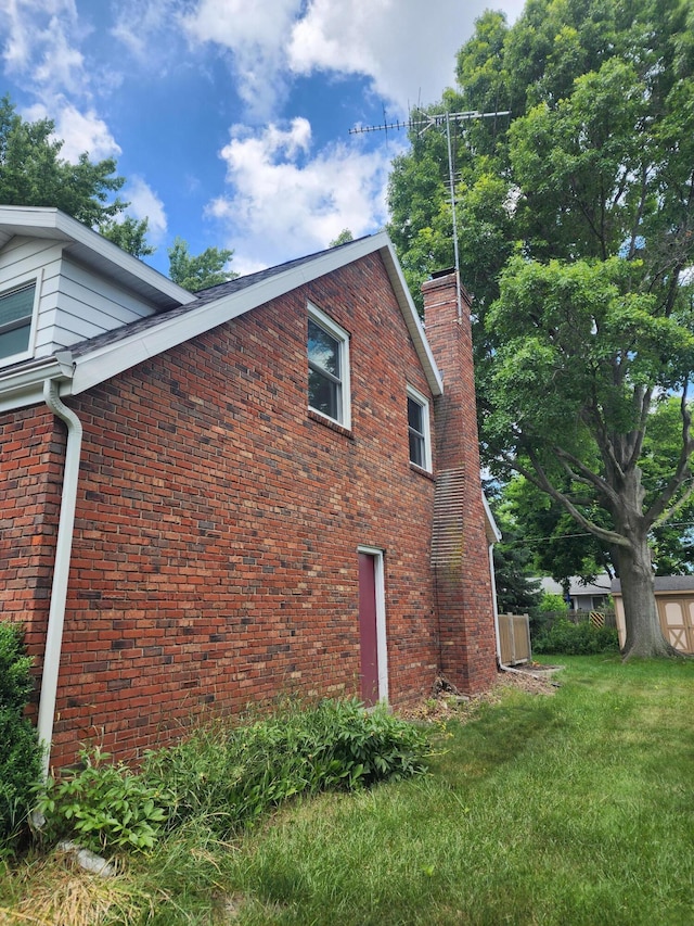 671 Lonesome Pine Trl, Saint Joseph, MI 49085 - view of side of home featuring brick siding, a yard, and a chimney