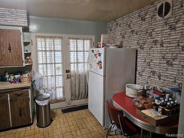 618 S Meade St, Flint, MI 48503 - kitchen featuring freestanding refrigerator, light countertops, open shelves, and brick patterned floors