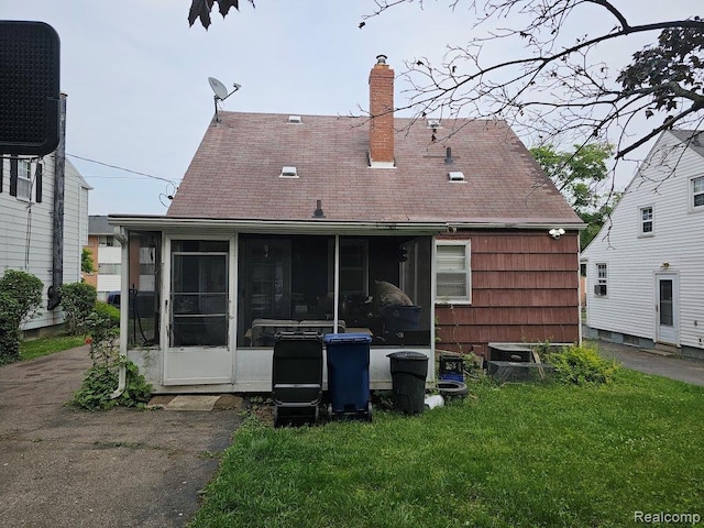 618 S Meade St, Flint, MI 48503 - back of house with a sunroom, a chimney, a lawn, and roof with shingles