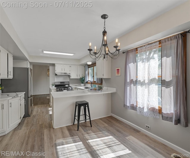 25067 Skye Dr, Farmington Hills, MI 48336 - kitchen with stainless steel range with gas stovetop, a peninsula, a chandelier, light countertops, and light wood-style floors