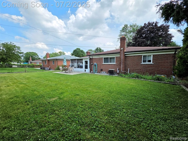 12137 Carol Ave, Warren, MI 48093 - rear view of property featuring a chimney, brick siding, a patio area, and a lawn